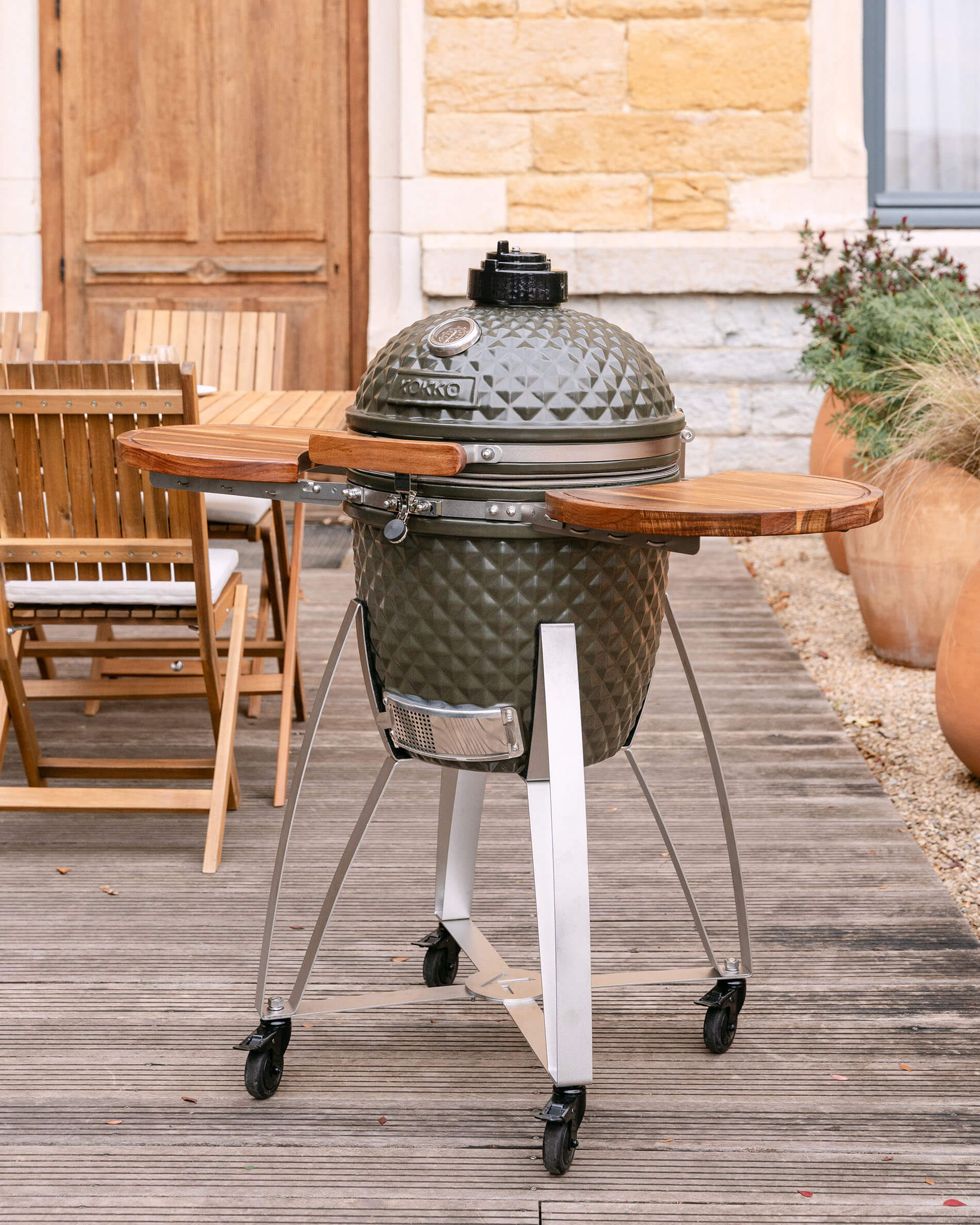 Kamado Kokko sur chariot mobile avec plateaux latéraux en bois, présenté en situation extérieure sur une terrasse.