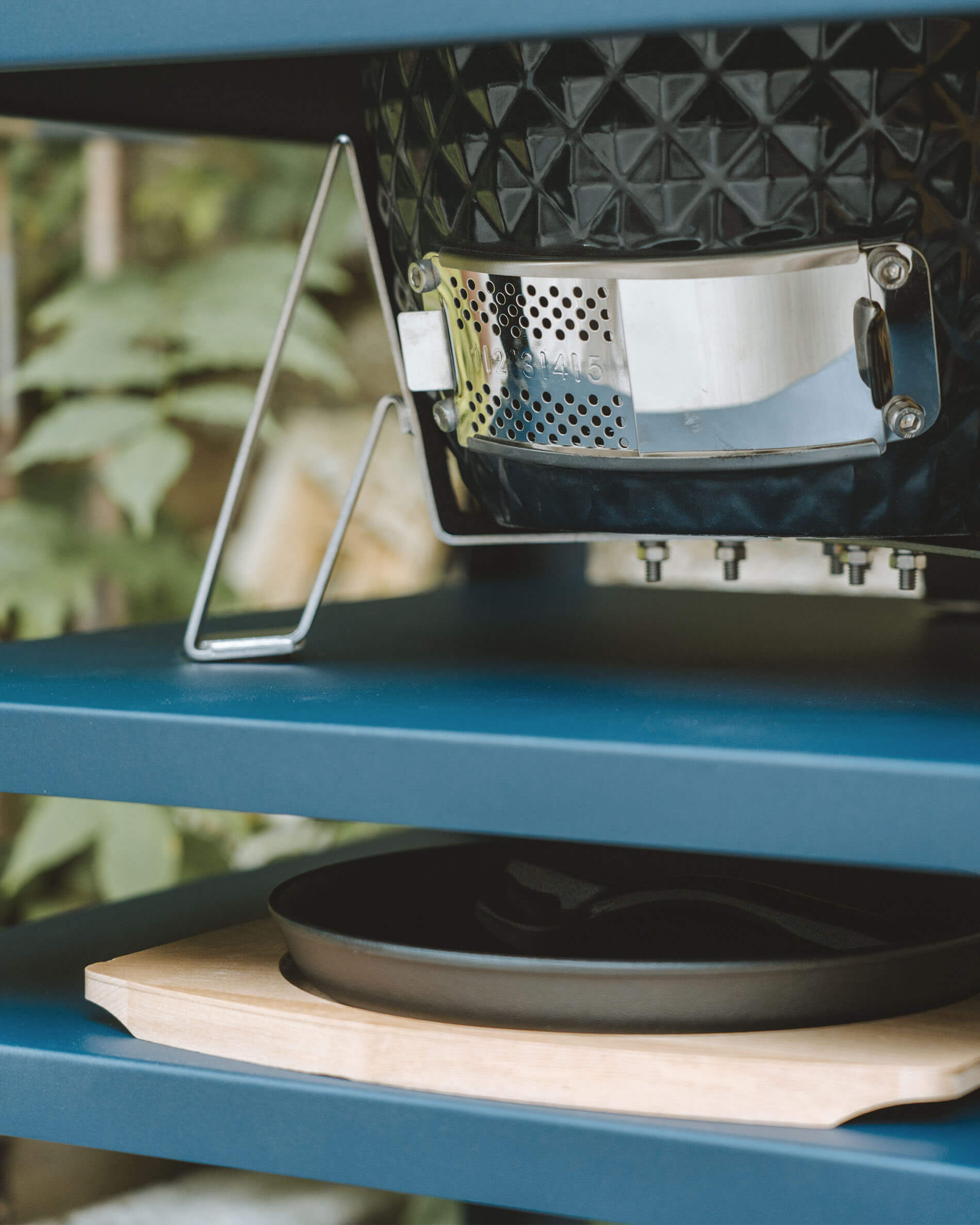 Gros plan sur la ventilation inférieure en acier inoxydable d’un kamado Kokko, intégrée à une desserte métallique avec bac récupérateur de cendres.