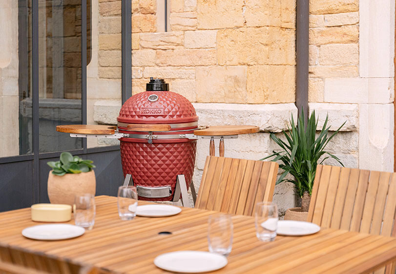 Espace de cuisson d’un kamado Kokko avec grille et accessoires en situation.