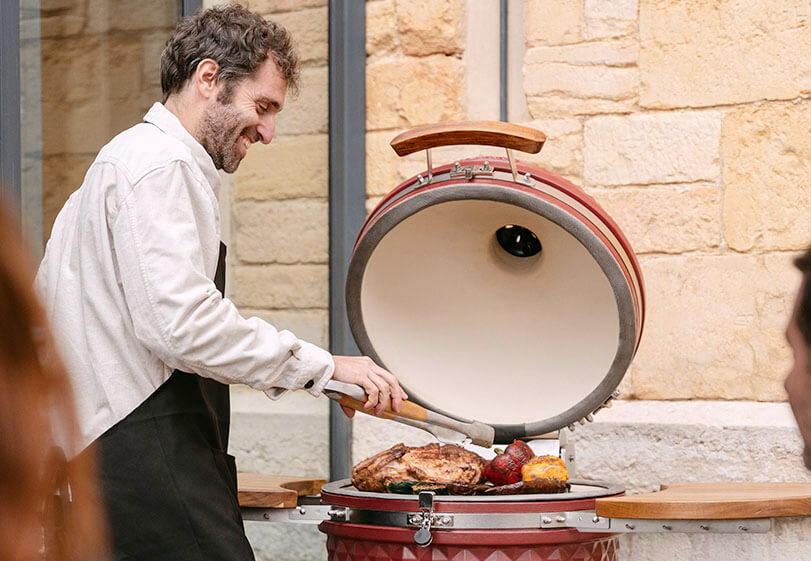 Expert Kokko utilisant un kamado rouge oxyde en extérieur pour démontrer les bonnes pratiques de cuisson.