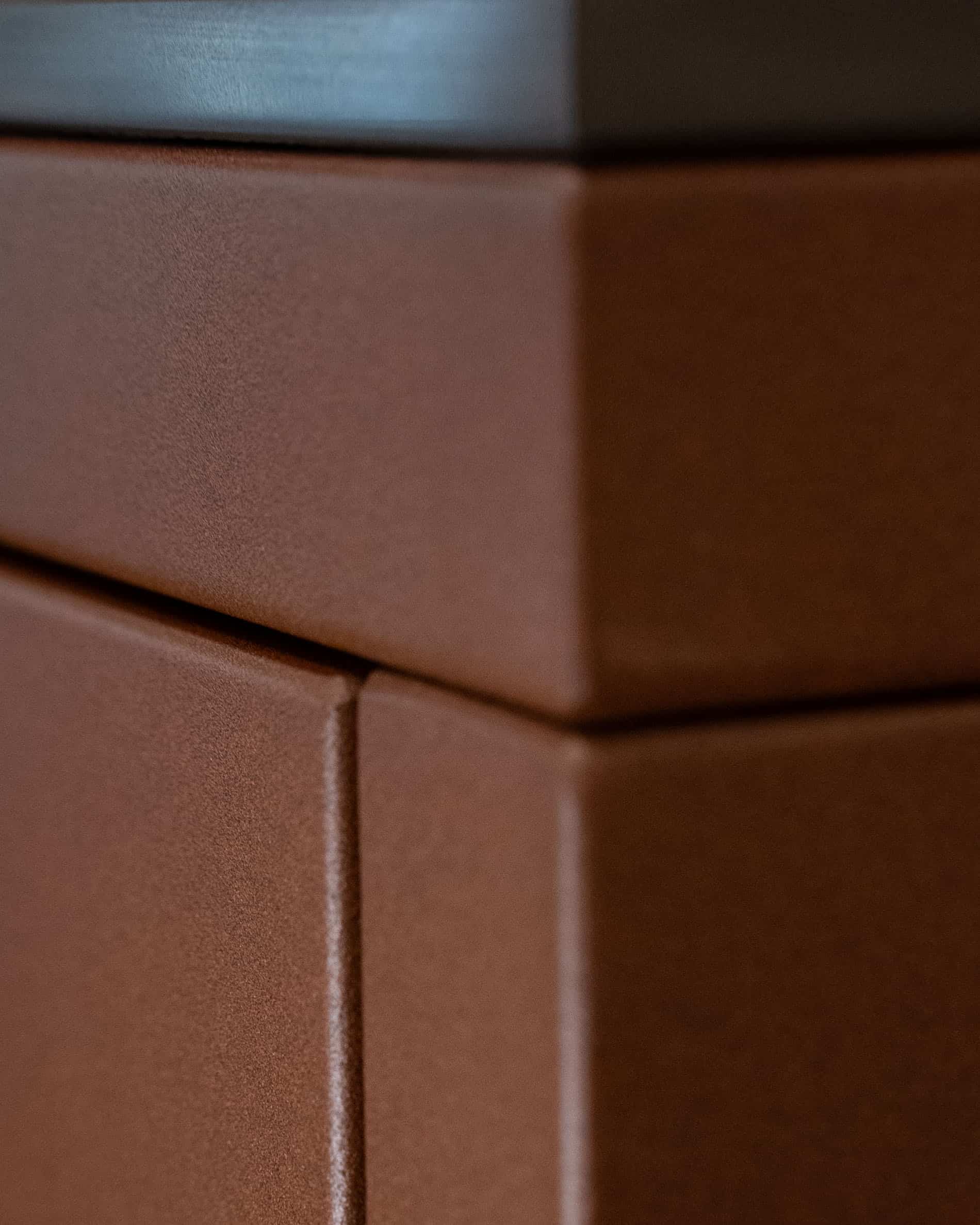 Détail de finition d’une cuisine pilotis, montrant l’angle du meuble, l’assemblage des panneaux et la texture mate de la façade coloris brun rouille.
