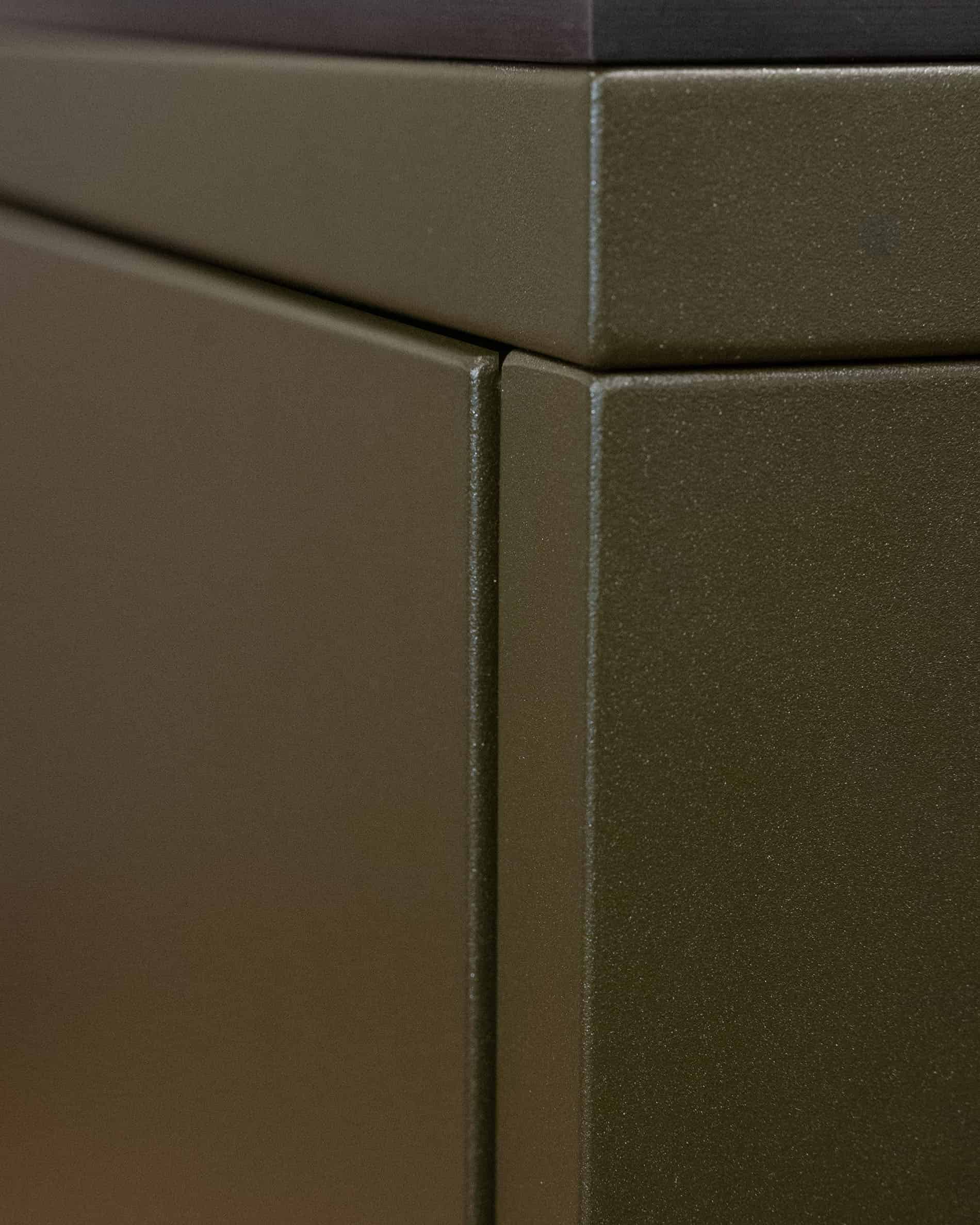 Détail de finition d’une cuisine pilotis, montrant l’assemblage des panneaux métalliques et la texture de la façade coloris olive.