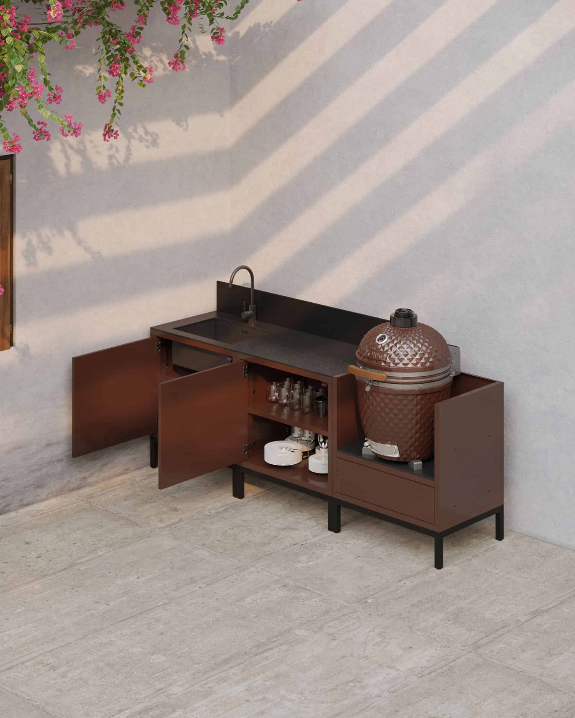 Cuisine pilotis en finition rouille avec portes ouvertes, plan de travail sombre, rangements intérieurs visibles et module kamado intégré pour une cuisine extérieure fonctionnelle.