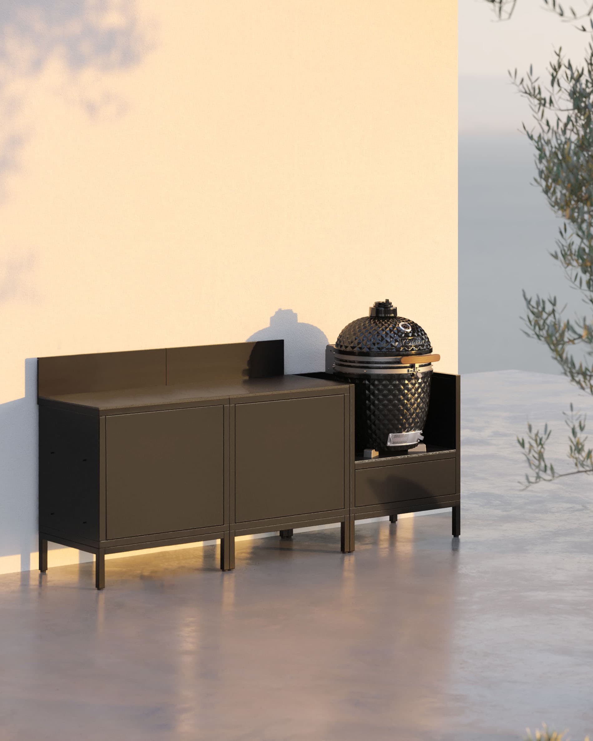 Cuisine pilotis 3 modules avec kamado, meuble noir, plan de travail sombre et rangements fermés, installation extérieure.